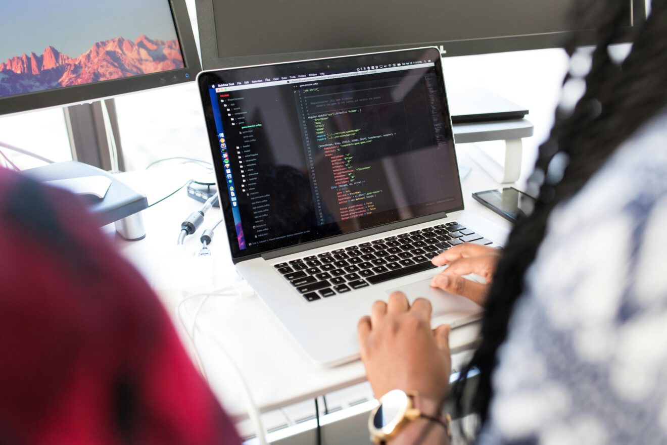 Eine Frau sitzt vor einem Laptop und programmiert